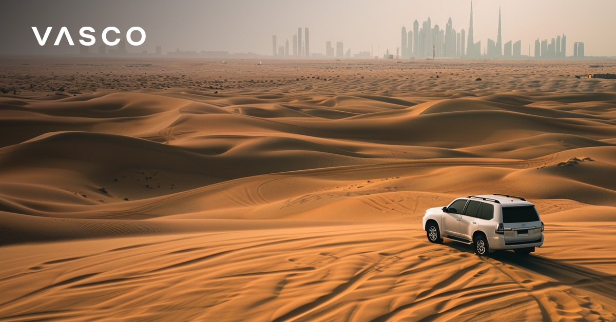 SUV projíždějící dubajskou pouští s panoramatem města v dálce