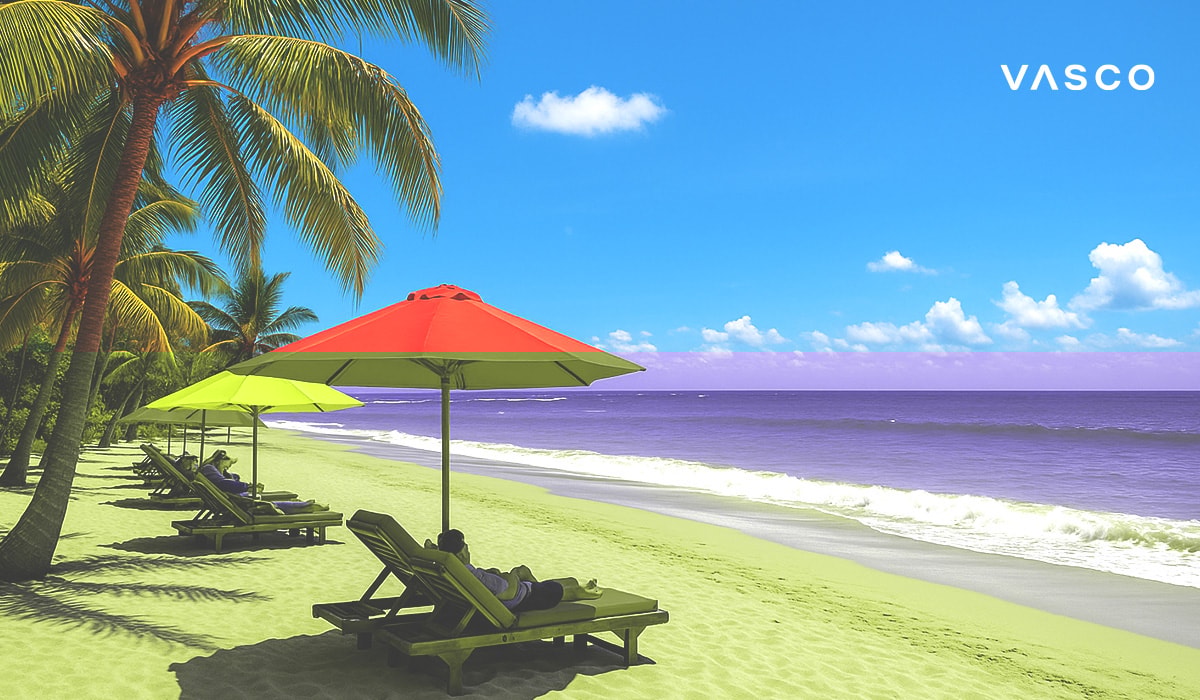 Turisté relaxují na lehátkách pod červenými a žlutými slunečníky na krásné písečné pláži s tyrkysovou vodou.