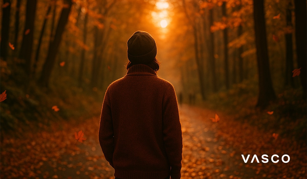 osoba v hnědém svetru procházející lesem s padajícím listím