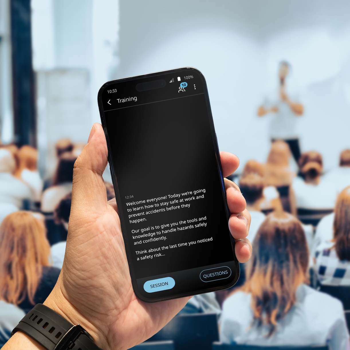 Vasco Audience V sále plném lidí probíhá přednáška. Muž drží v ruce telefon, na kterém se pomocí aplikace Vasco Audience zobrazuje překlad.