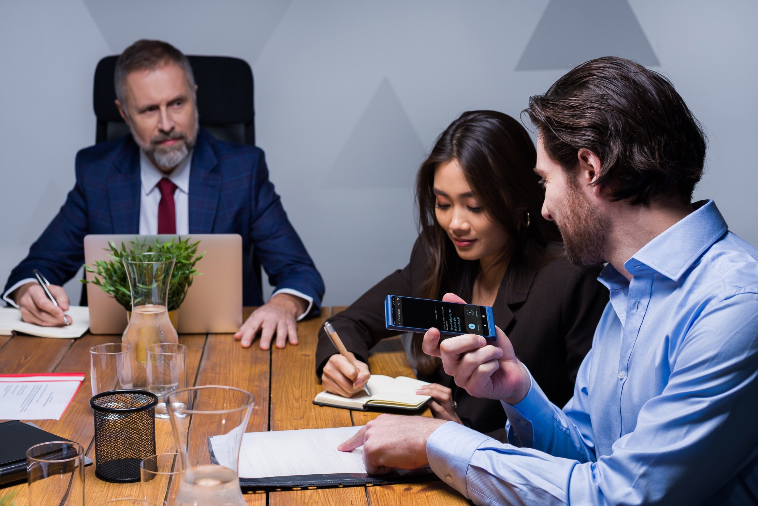 Usmívající se lidé na obchodním jednání, kteří spolu komunikují prostřednictvím aplikace Vasco Translator.