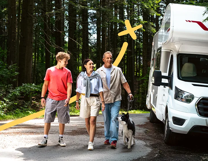 Tříčlenná rodina – dva rodiče a jedno dítě a pes, která se za slunečného dne vzdaluje od svého zaparkovaného obytného vozu. Usmívají se, povídají si a užívají si společné chvíle.