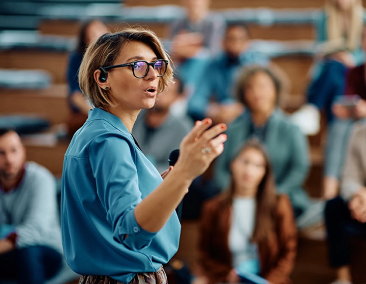Žena přednáší na univerzitě s překladačem Vasco Translator E1 v uchu.
